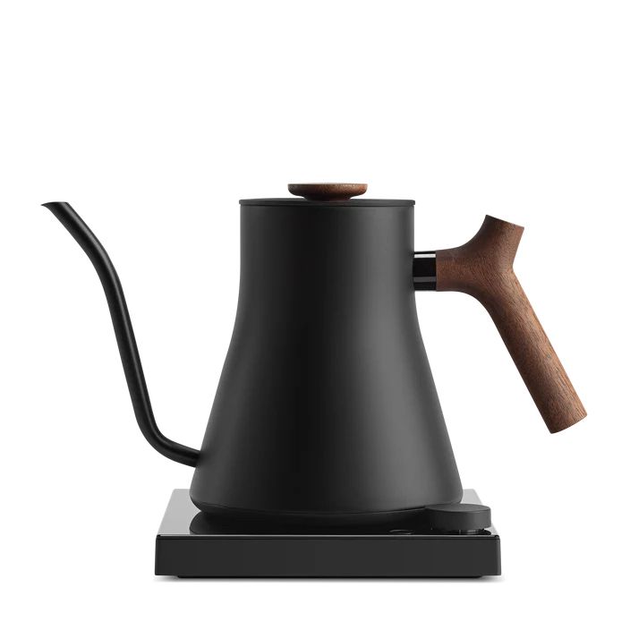 Ghosted photography of the Fellow company’s flagship kettle. It is a matte black, adorned with a dark spruce handle. The spout is remarkably spindly.