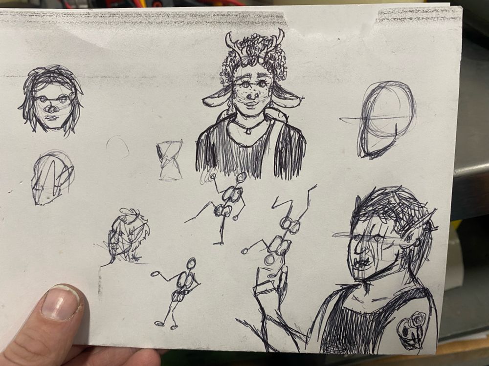 Various pen sketches on a piece of paper, includes stick figures, an orc-looking character, a character with deer antlers and ears, and several half-sketched faces