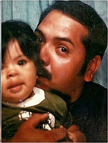 A photo booth picture of a man in his 30s, my dad, snuggling with a baby around a year old, myself. 