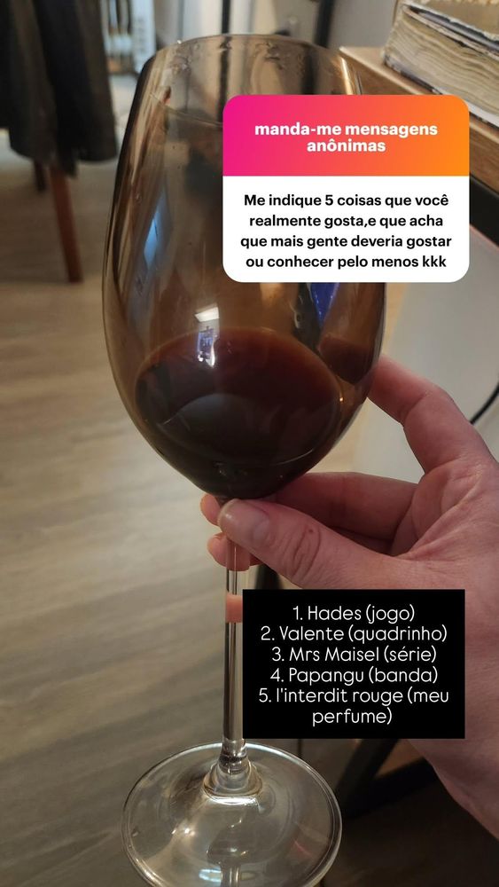caixinha: me diga 5 coisas que vc realmente gosta e que acha que mais gente deveria gostar ou conhecer pelo menos. foto mostrando uma taça de vinho tinto quase vazia. resposta: 1. Hades (jogo) 2. Valente (quadrinho), 3. Mrs. Maisel (série), 4. Papangu (banda), 5. L'interdit rouge (meu perfume) 