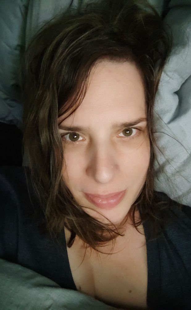 Bild von mir im Bett unter der Decke liegend mit dem Kopf auf einem Polster.