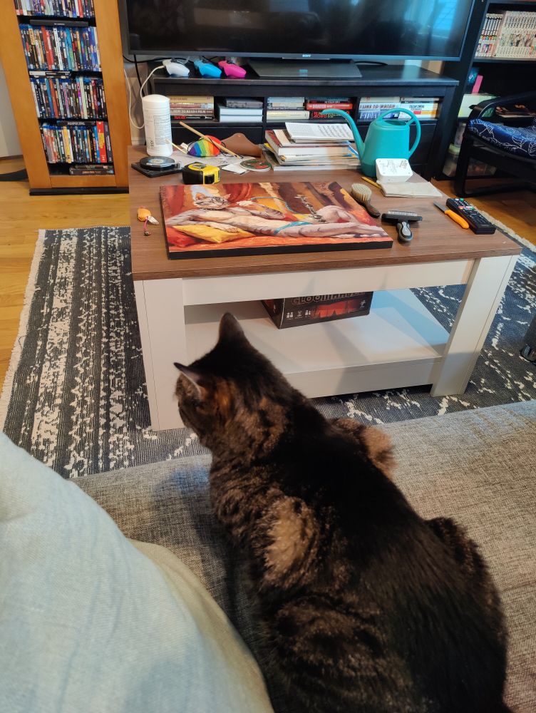 Giving my cat body dysmorphia

A photo of a cat on a couch with a painting on the coffee table in front of them