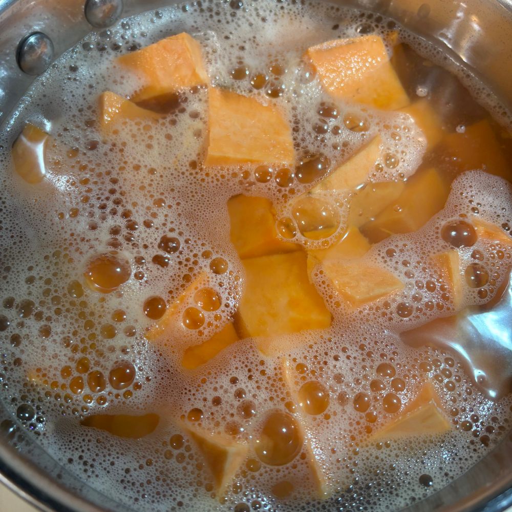 Sweet potatoes, cubed, boiling in a pot.
