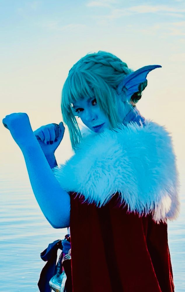 Erika cosplaying Gentle from TransplanarRPG. They’re looking at the camera over their shoulder with their fists raised as if getting ready for a fight. 