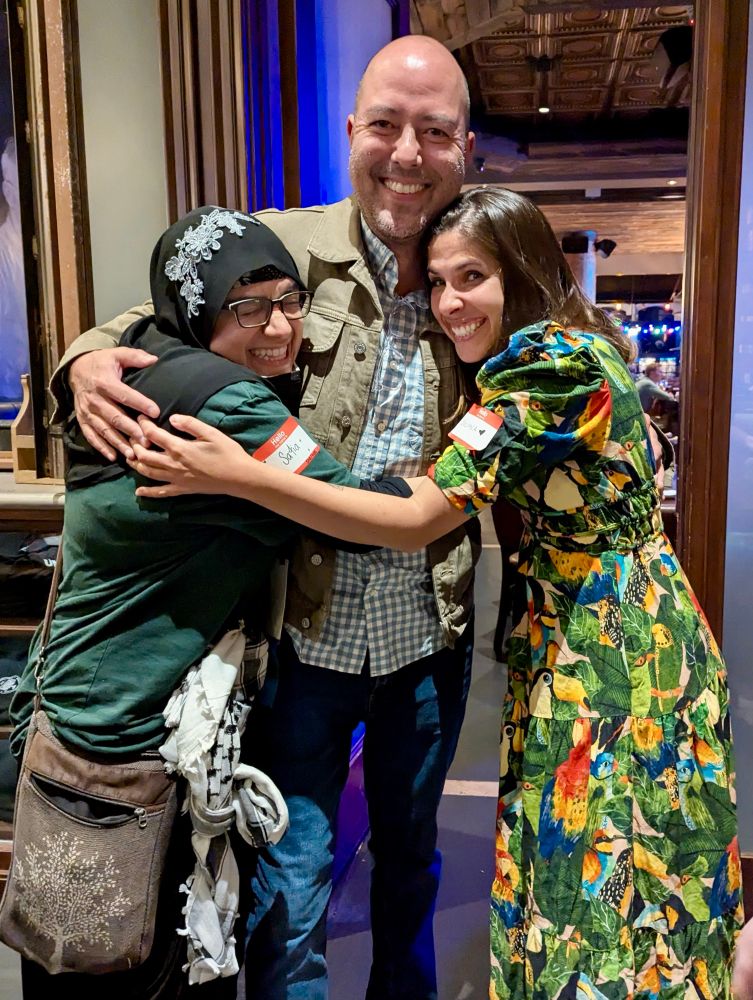 Safia and Juliana hugging Peter. 