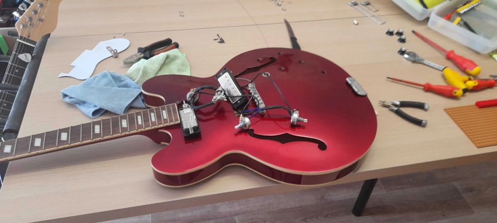 partially disassembled guitar, messy wires hanging out
its a red epiphone riviera model