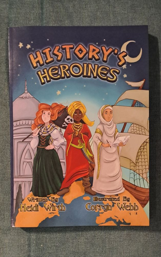 Image is a photo of a book, with the title History's Heroines. There are 3 women on the cover of different nationalities, standing on top of the world. 