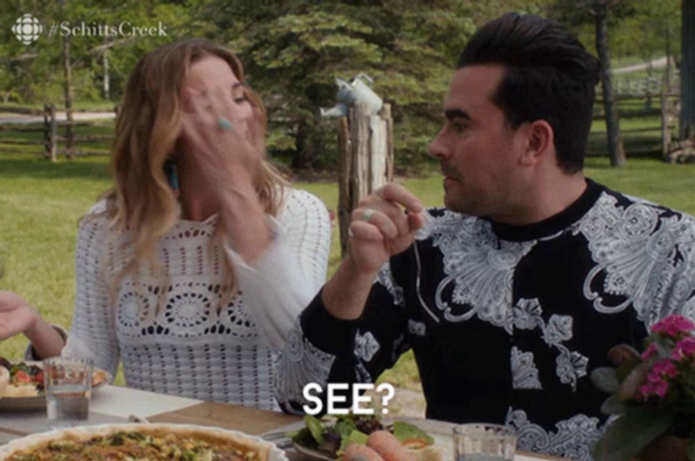 a man and a woman sitting at a table with a sign that says see on it