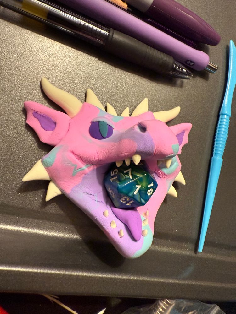 A dragon face with mouth open. The color is swirling pink, purple, and aqua. The eyes are purple and teal. I added a little tongue to this one and reduced the number of teeth (since they were hard to stick in. It also has more horns and jaw spikes, and pink ears w/ purple centers (illusion of depth).