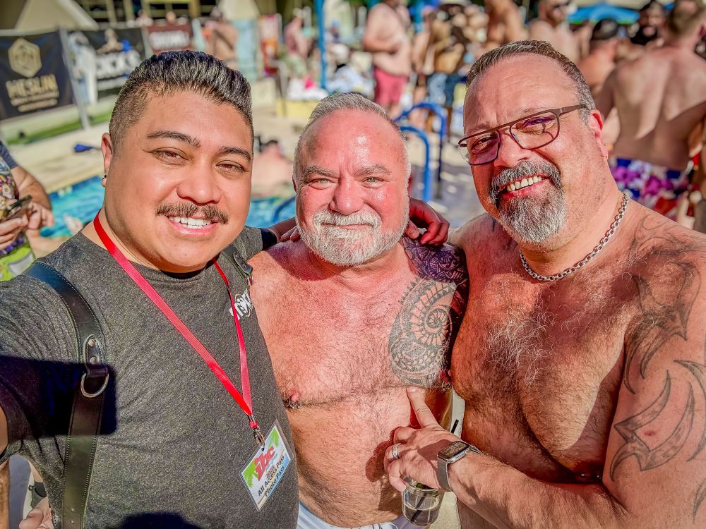 three men enjoy a selfie at a pool party