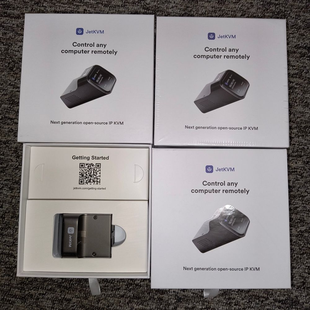 Photo of three JetKVM boxes with one opened to show device itself