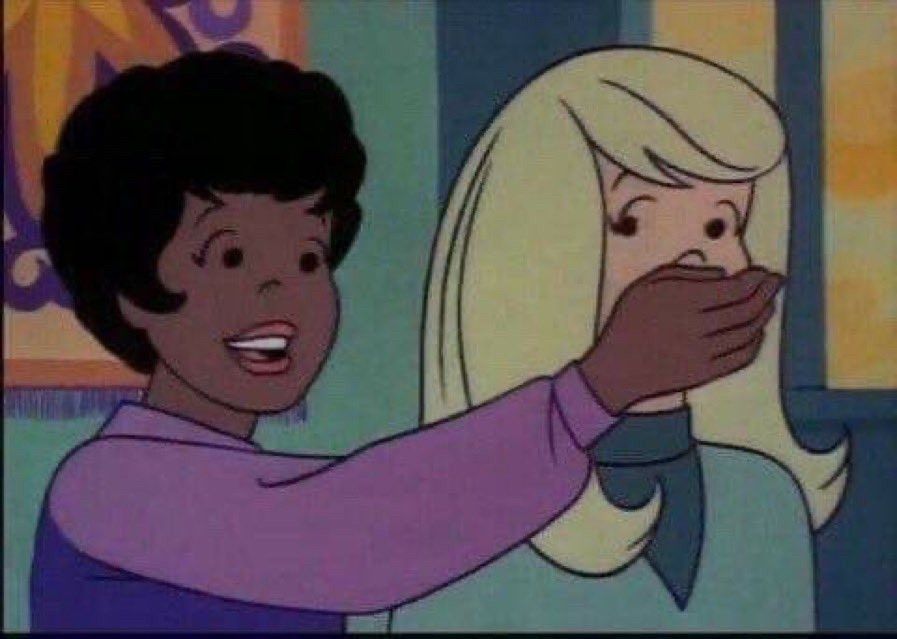 A Black lady cartoon character has her hand over the mouth of a white lady cartoon character to keep her from speaking.