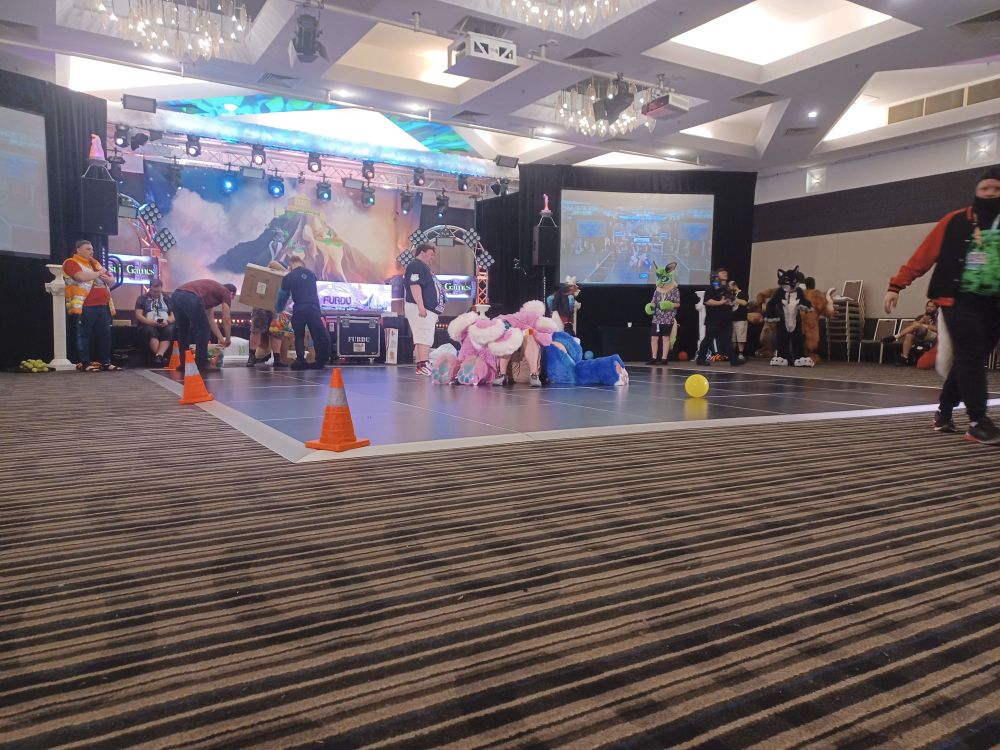 A pair of fursuiters dogpiling the Fursuit games announcer