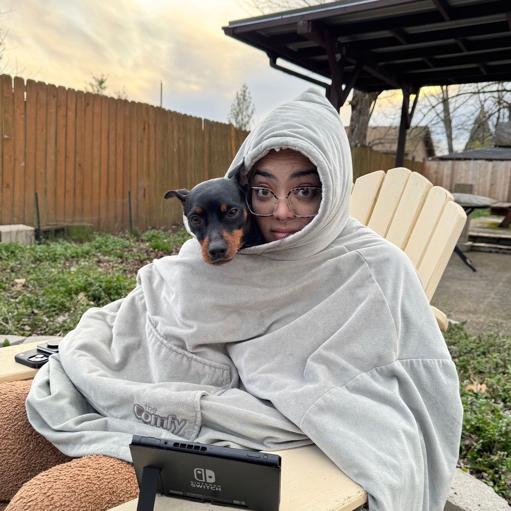 A human and a dog in a comfy playing a switch. 