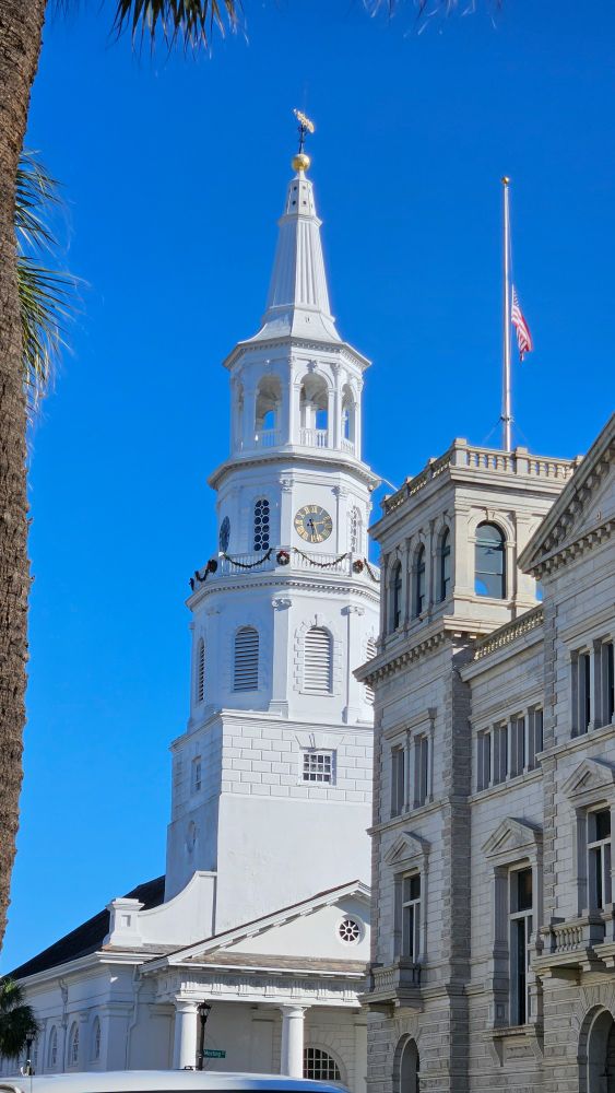 St Michael's white steeple. The nearby flag in the foreground is over the US Post Office and is at half mast for President Carter. These two buildings are half of the so-called Four Corners of Law, at Broad and Meeting streets.