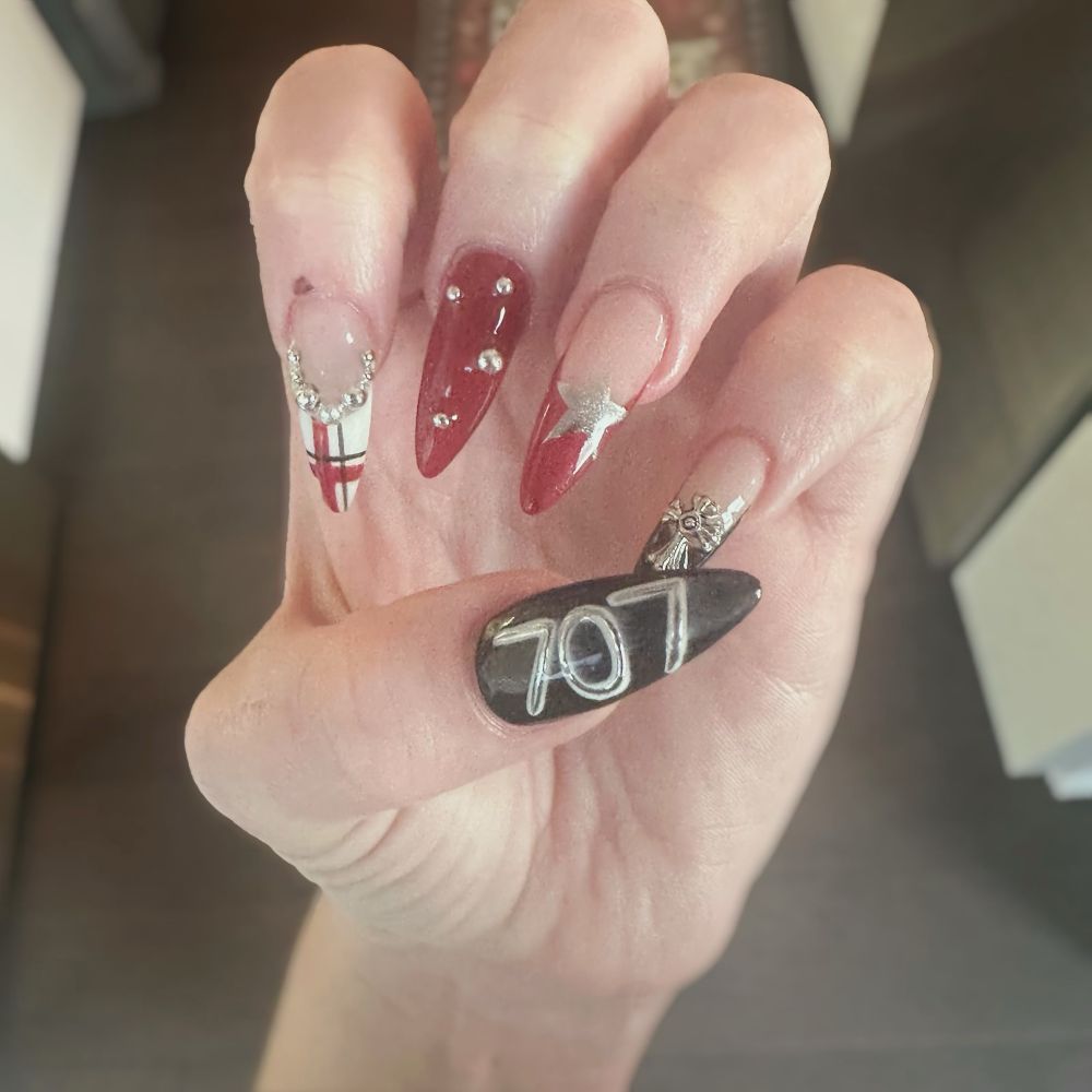Another picture of Pink’s nails, the index finger with a red, black and white plaid. There’s a chrome star on her ring finger, and a cross charm on her pinky finger. Her thumb reads “707,” the apartment featured in the show. 