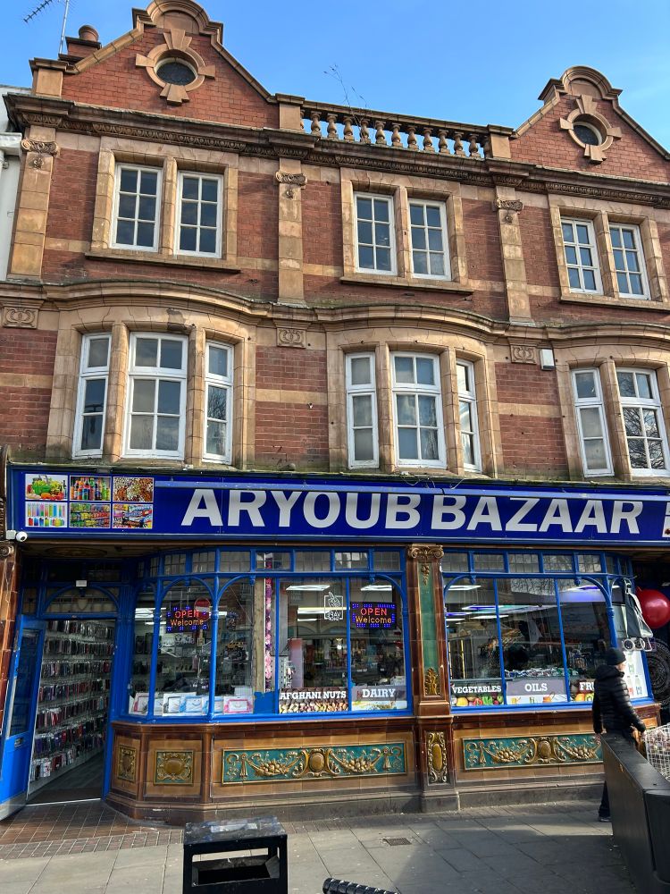 Handsome shop, delicate window openings stone dressing & string course, pale brick, majolica-like tiles. 