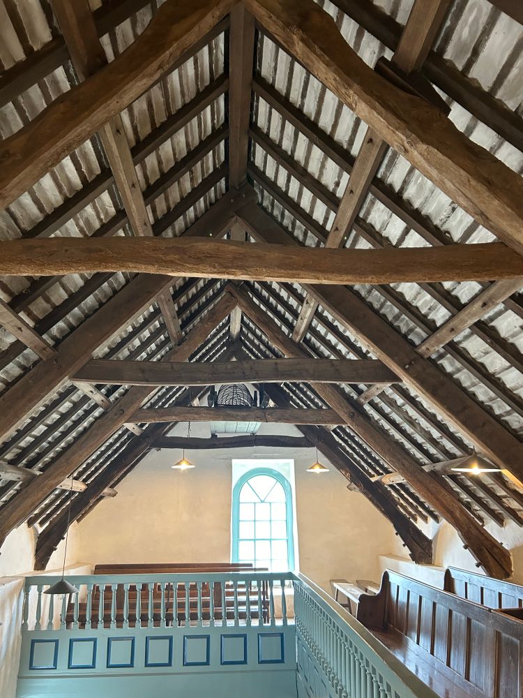 First floor gallery with unpainted wooden pews.  Funeral bier tucked in the eaves. 