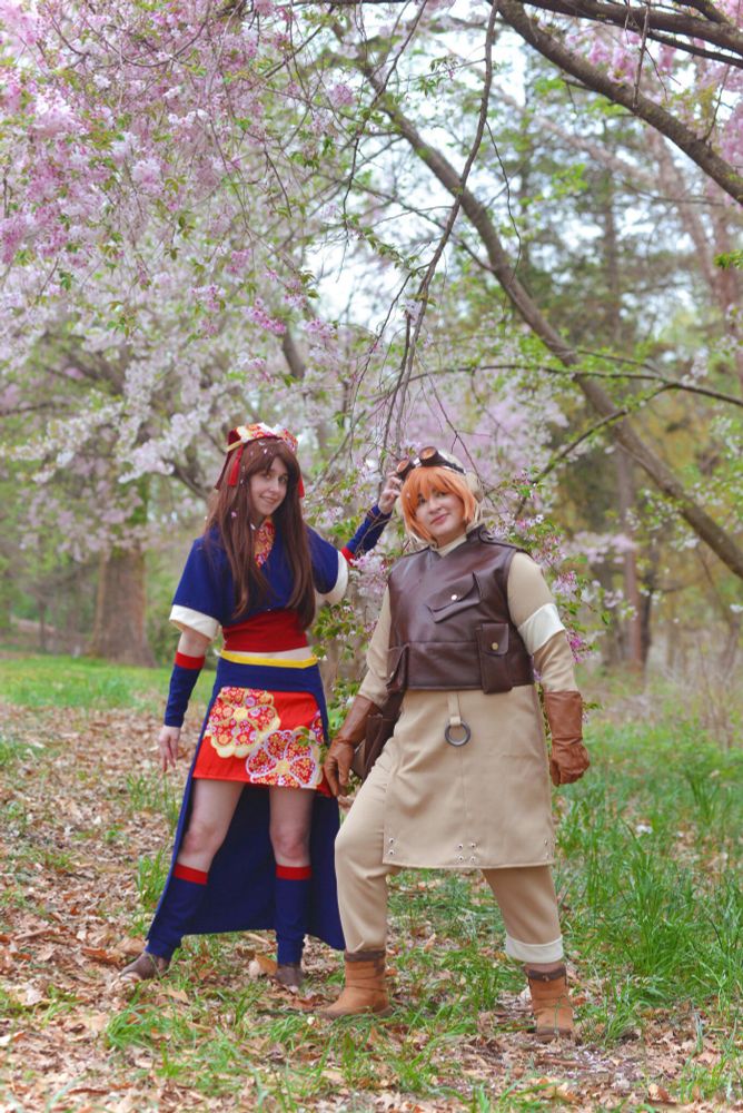 Two cosplays of Kirara Mikumari and Heihachi Hayashida from the anime Samurai 7. The cosplayers are standing in front of a cherry blossom tree. 