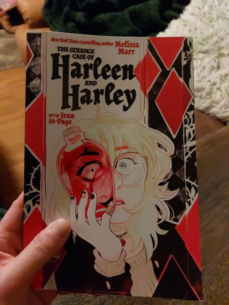 Comic book cover of "The Strange Case of Harleen and Harley". It shows Harleen Quinzel peering through a flask of red liquid. Through the liquid, her face features expressions of her alter ego Harley Quinn. 