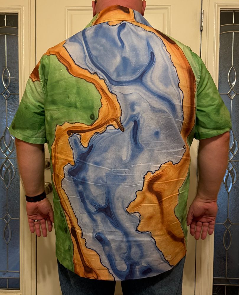 A man wearing a casual shirt depicting an overhead view of a river landscape.