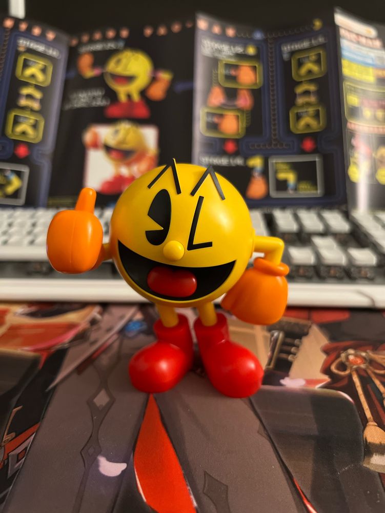 Snap-built model kit of PAC-MAN giving a thumbs up in front of the full-color building instruction booklet.