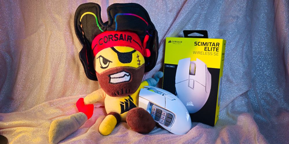 A picture of my Corsair pirate plush next to the Scimitar Elite Wirless mouse in white. There's a glittery pink background.