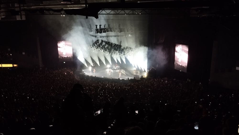 The 3Arena in the darkness except for several white spotlights on the stage that are revealing the silhouette of Måneskin's members.