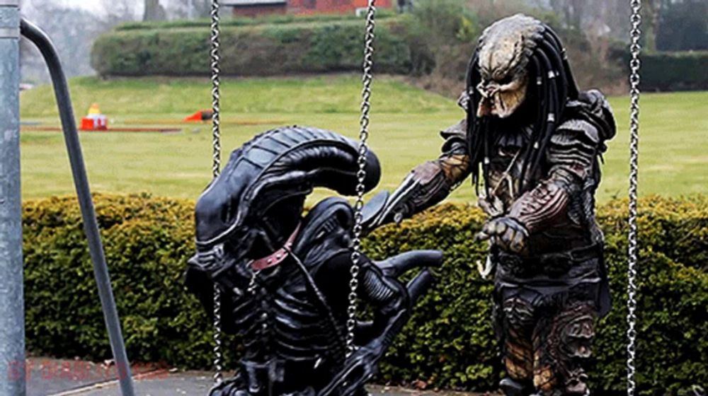 a predator is playing with an alien on a swing