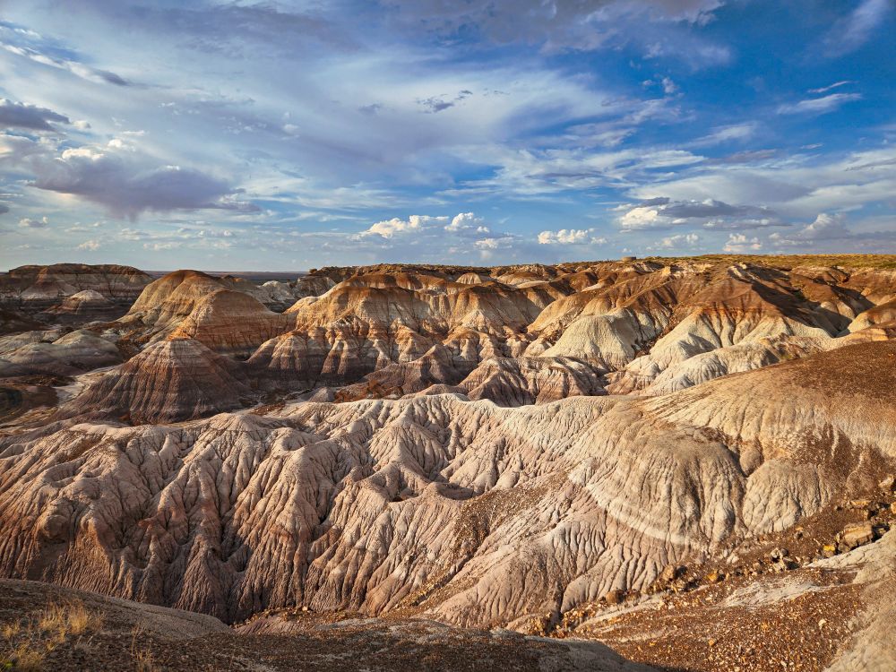 Image of hills in Petrified Forest set against a blue sky with scattered clouds. 