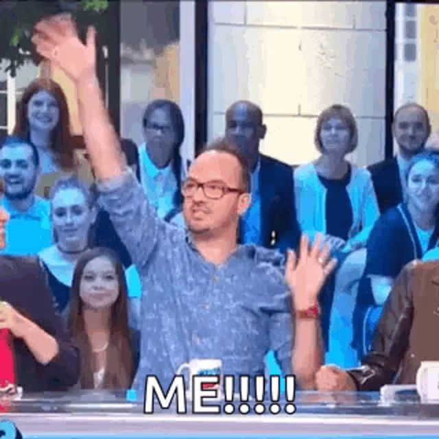 a man is waving his hand in front of a crowd of people on a television show .