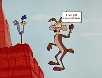 Wile E Coyote midair holding a sign that says 