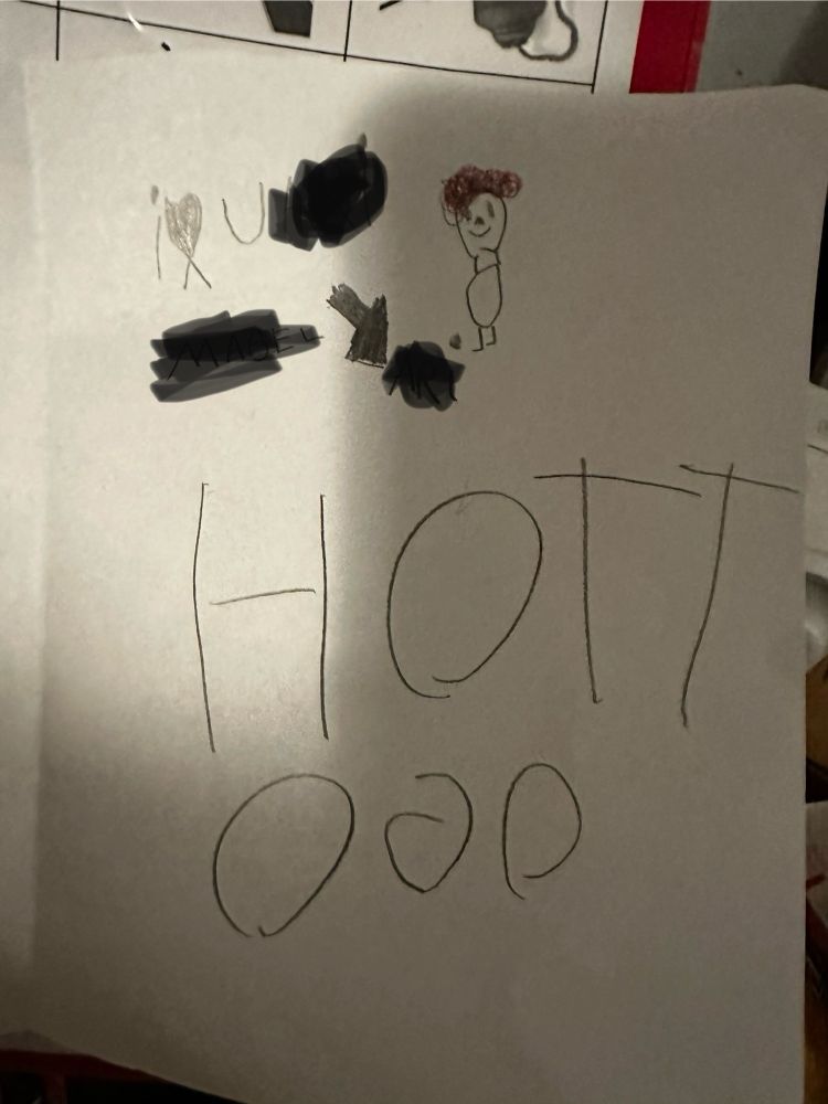 Card made by a child that says “I [heart drawing] U [redacted name]”. There is a picture of a small boy with curly red hair. Then in large letters, all as one word “HOTTOGO.” The G is backwards.