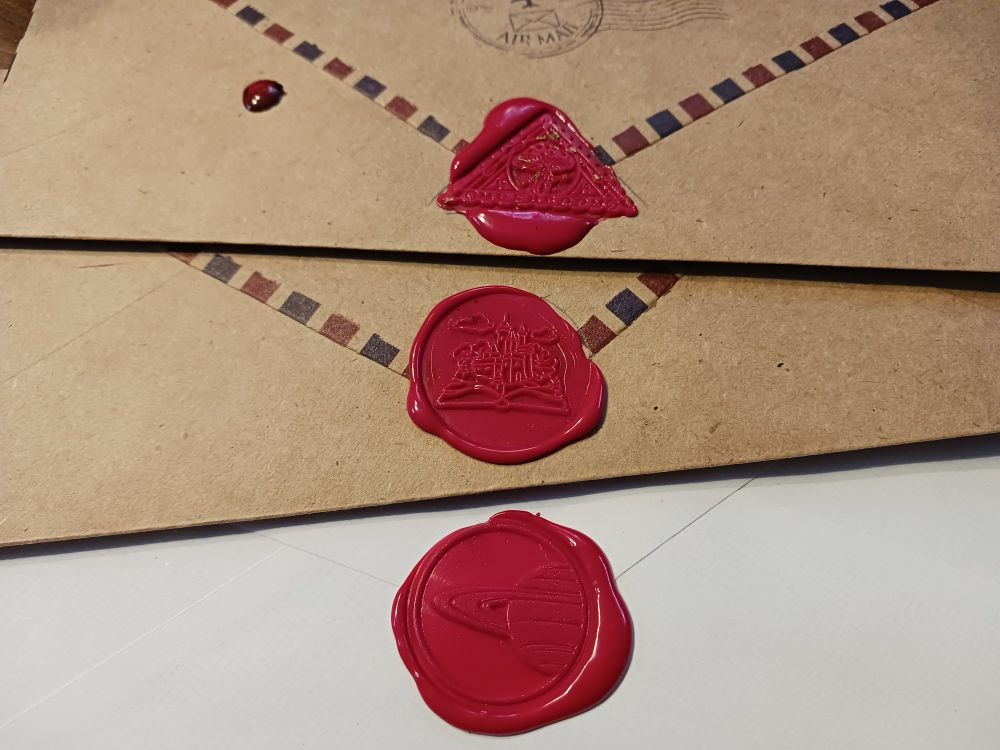 3 wax seals: a triangular mushroom seal, a fantasy kingdom seal, and a saturn seal