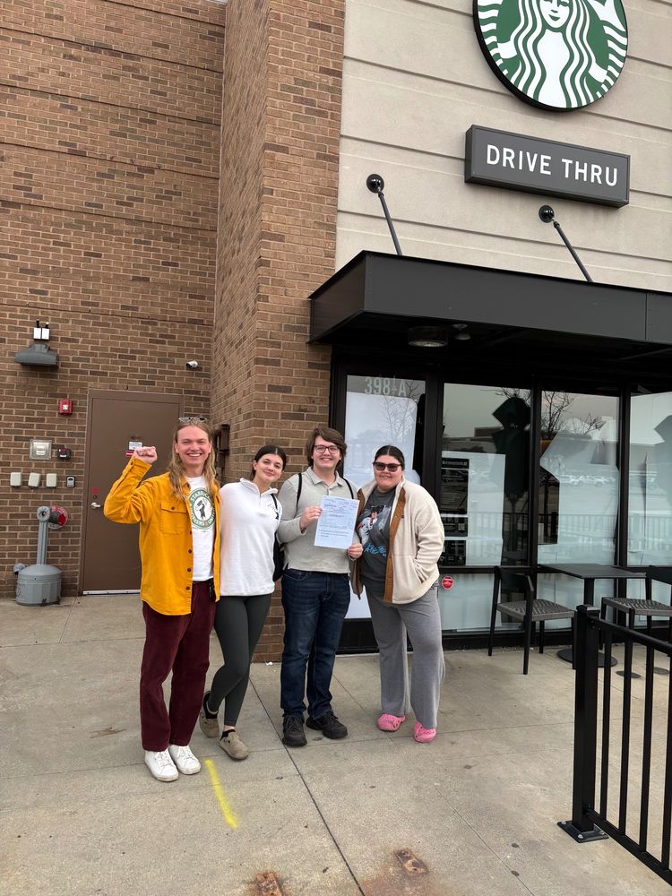 Four SBWU members pose in front of their Starbucks store after winning their union election
