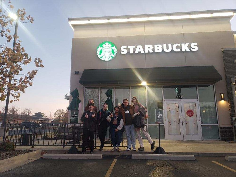 A group of 6 SBWU members and allies support their union victory outside of a Starbucks store
