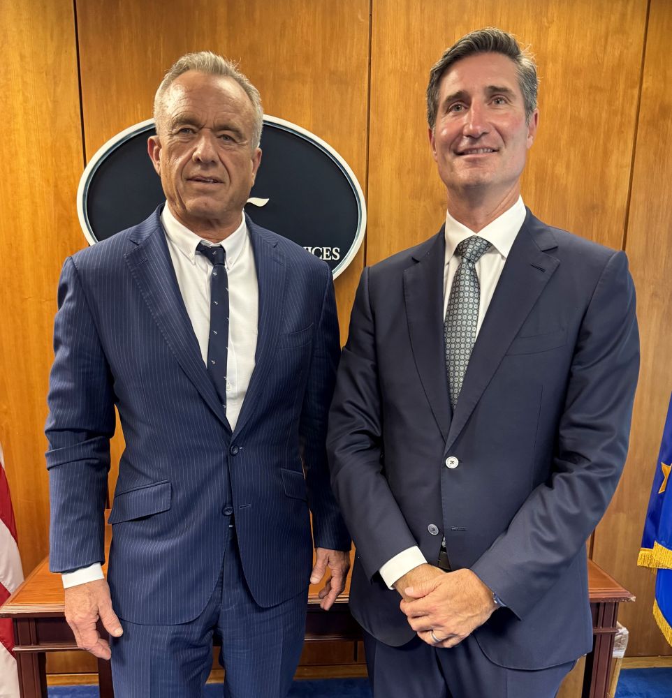 Starbucks CEO Brian Niccol smiles and poses with RFK Jr in a government building 