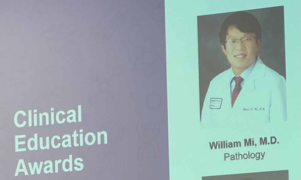 A photo of Dr Mi wearing a white coat on the big screen 
