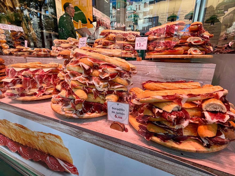 Giants stacks of amazing looking sandwiches in a storefront window 