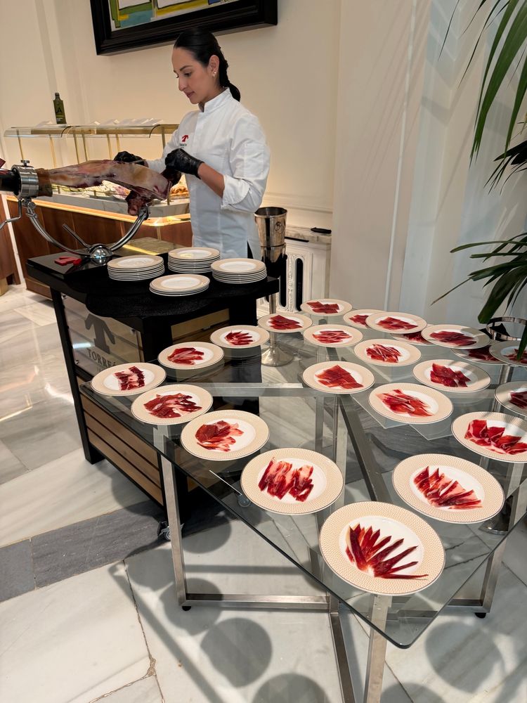 Plates of iberico ham and a woman carving them 