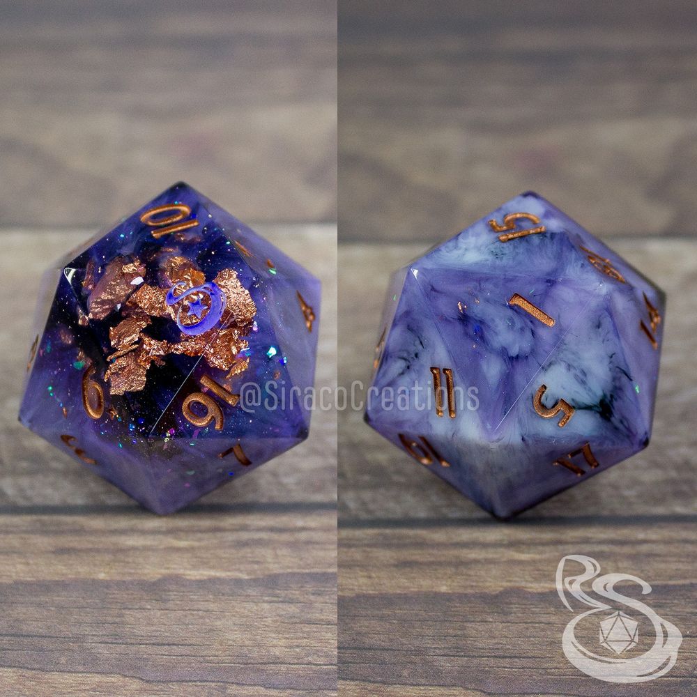 A chonky 45mm D20 with the numbers smaller and in the right hand corner. There are swirls of color, copper flakes, and chameleon flakes. The 20 has been replaced with a stylized S and a star. This image shows both the high face and low face of the d20.