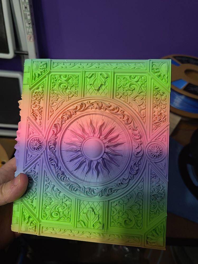 A 3D printed storage tome for not only TTRPG players, but you can use them for anything! The outside tome has a unique design, while the faux pages hide the secret storage compartments. This tome has a 3D image of a sub in the center, with intricate braque textures on the cover. The filament used is a rainbow gradient filament.