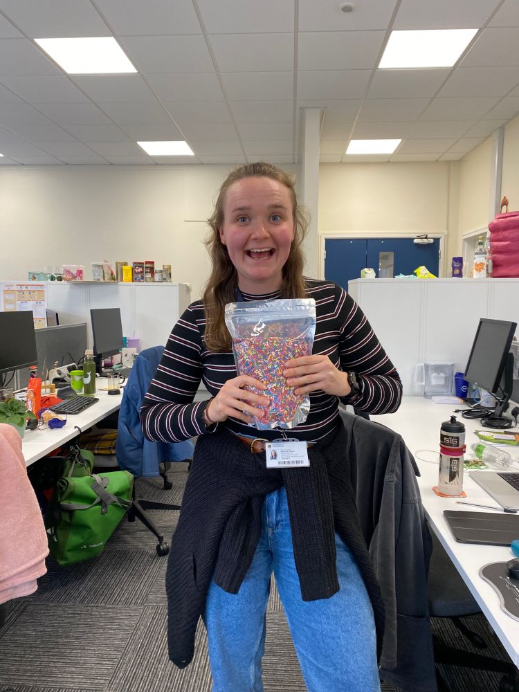 A woman holding a giant bag of cake sprinkles