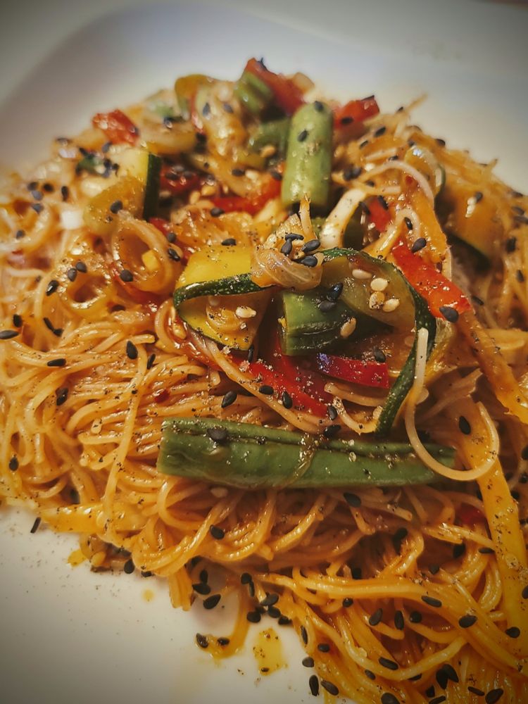 Ein asiatischer Nudelsalat mit verschiedenen Gemüsesorten, brauner Sauce und schwarzem Sesam drauf