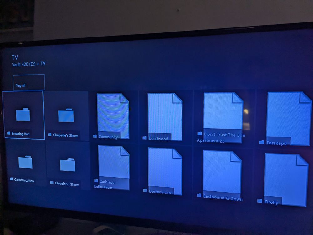 File explorer interface on a TV showing a bunch of folders for banger TV shows:
Breaking Bad
Chappelles Show
Community
Deadwood
Don't Trust the B in Apt 23
Farscape
Californication
Cleveland show
Curb Your Enthusiasm 
Dexter's Lab
Eastbound & Down
Firefly
