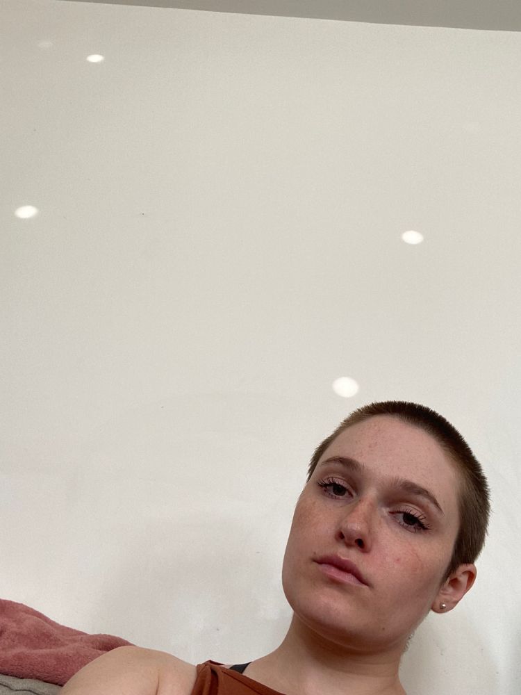 Year-old selfie of me - 29-year-old white woman with buzz cut brown hair. It’s just my head in the bottom right corner against a plain white wall. I look a little moody and maybe a little stoned.