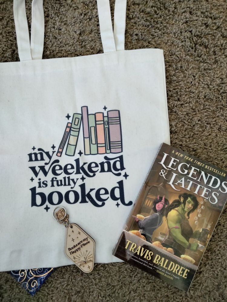 Tote bag "my weekend is fully booked," keychain "reading is my happy place," and the book Legends and Lattes by Travis Baldree.
