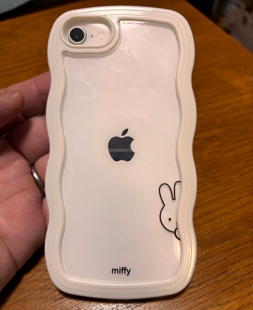 iPhone SEの背面。白いボディ。ミッフィーのケースが取り付けられている