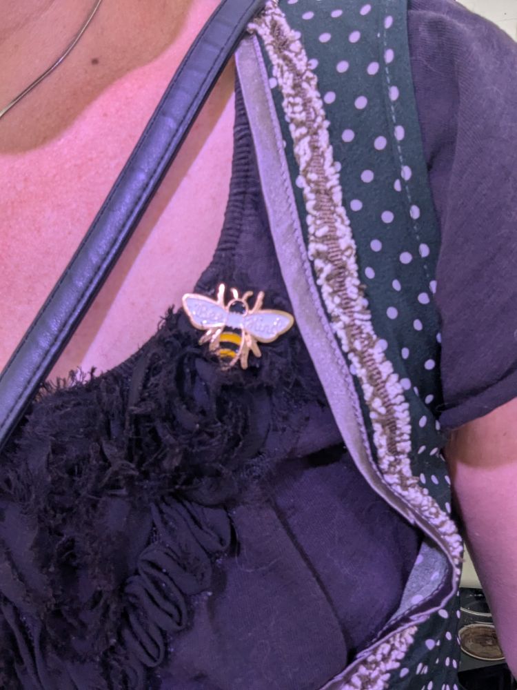 An enamel bee pin on a woman's blouse