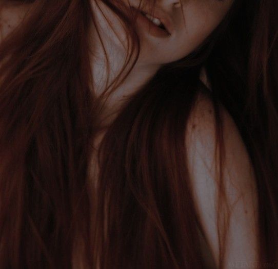 Foto de una chica de pelo cobrizo y liso y largo con los labios entreabiertos. Solo se le ve la mitad del rostro inferior. 